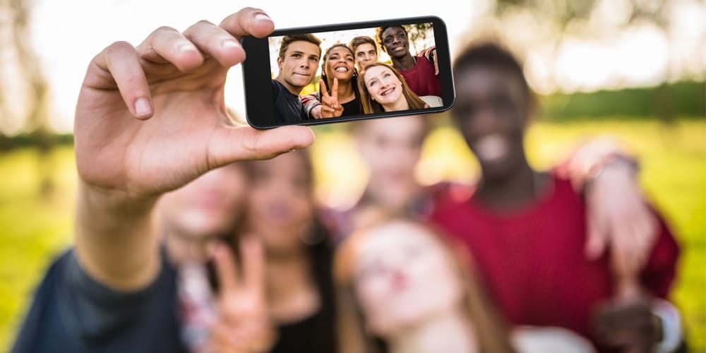 Young adults standing together to take a selfie.